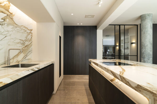 Luxe keukeneiland in eiken fineer met doorlopend gouden keramiek, naadloos geïntegreerd in het ontwerp
